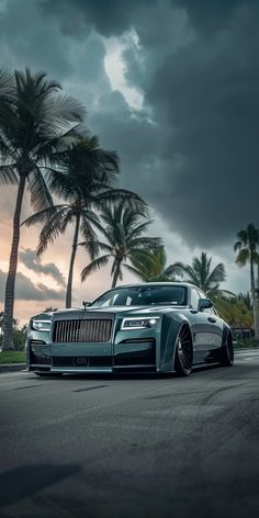 a rolls royce parked on the side of a road with palm trees in the background