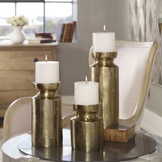 three candles sitting on top of a table next to a chair in a living room