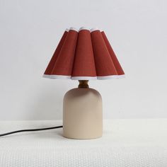 a table lamp with a red shade on it's base and a black cord