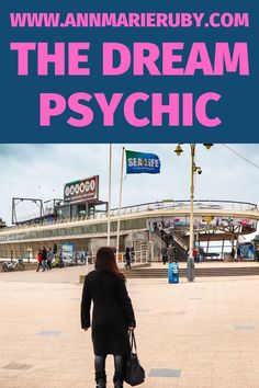 a woman walking across a parking lot next to a sign that says the dream psychic