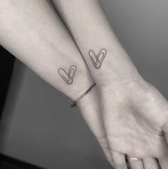 two people holding hands with tattoos on their arms and one has a heart in the middle