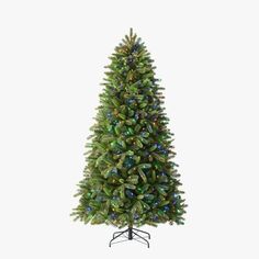 a green christmas tree with lights on it's branches and a black stand in front of a white background