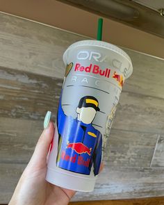 a person holding up a starbucks cup with an image of a red bull on it