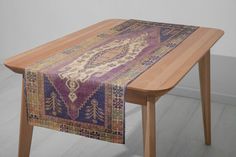 a wooden table topped with a purple and blue rug