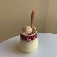 a dessert in a glass on top of a table with a wooden spoon sticking out of it