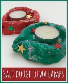 two small candles sitting on top of each other in front of a red and green wreath