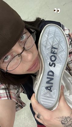 a woman wearing glasses holding up a pair of shoes