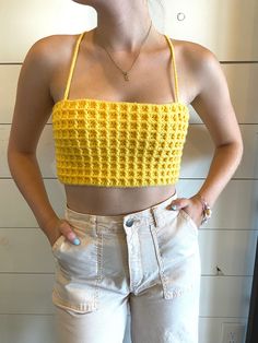 a woman standing in front of a wall wearing white shorts and a yellow crop top