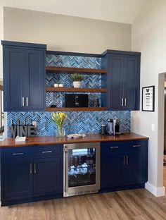 a kitchen with blue cabinets and wooden counter tops in front of a wall mounted oven