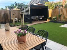 a wooden table sitting on top of a lush green field next to a small shed