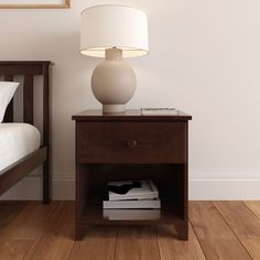 a nightstand with a lamp on top of it next to a bed