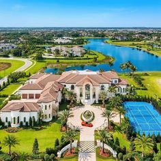 an aerial view of a large mansion with a tennis court in the foreground and water behind it