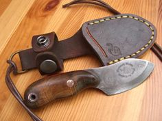 two knives sitting next to each other on top of a wooden table with leather straps