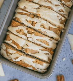 a loaf of bread with icing and pecans around it on a blue surface