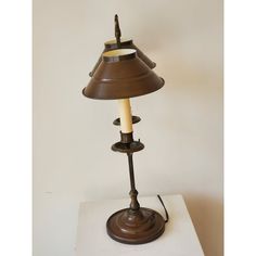 a lamp that is sitting on top of a white surface with a brown shade over it