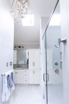 a bathroom with white cabinets and a chandelier hanging from the ceiling above it