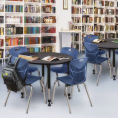 there are many chairs and tables in the library with bookshelves behind them,