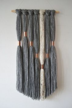 the wall hanging is made out of yarn and wooden dows, with several tassels attached to it