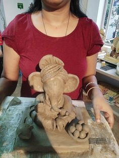 a woman is making an elephant statue out of clay