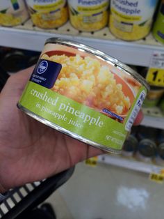 a hand holding a can of canned pineapple macaroni and cheese in a grocery store