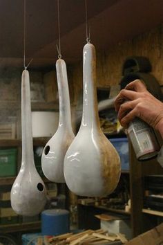 three white vases hanging from strings in a shop