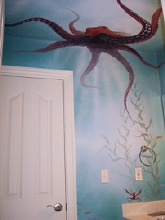 an octopus painted on the wall in a bathroom next to a sink and door,