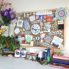 a bulletin board covered in lots of stickers and magnets next to some flowers