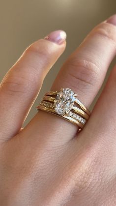 a woman's hand with two wedding rings on top of her ring and the other half of her finger