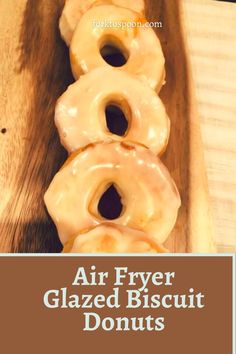 four glazed doughnuts sitting on top of a wooden tray with the words air fryer glazed biscuit donuts