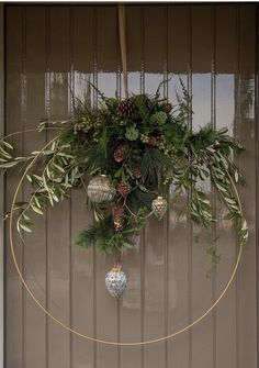 a wreath with pine cones and evergreens hanging from the side of a garage door