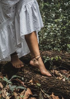 a woman standing on top of a tree trunk in the middle of some leaves and trees