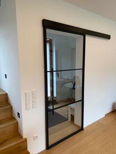 an open door leading to a living room with wooden floors and stairs in front of a white wall