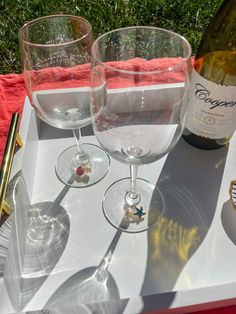 two wine glasses sitting on top of a white tray next to a bottle of wine