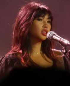 a woman with red hair singing into a microphone