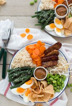 two plates filled with different types of food on top of a wooden table next to utensils