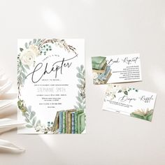 wedding stationery with books and greenery on white paper, next to folded cards