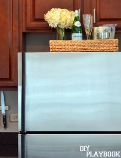 a silver refrigerator freezer sitting inside of a kitchen next to wooden cupboards and white flowers