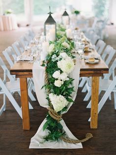 a long table with white flowers and greenery