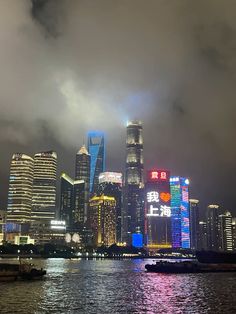 the city skyline is lit up at night with bright lights and clouds in the sky