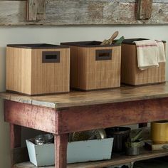 three bins on top of a wooden table with baskets and other items in them