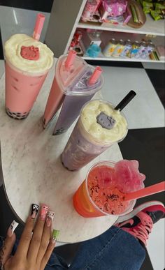 three drinks are sitting on a table next to each other and one is holding a manicure