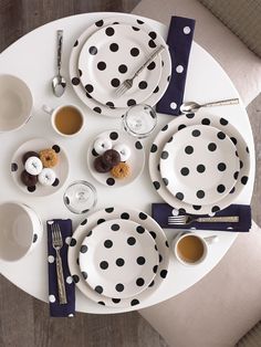 a white table topped with black and white polka dot plates, cups and saucers