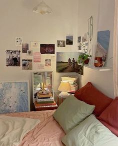 an unmade bed with many pictures on the wall