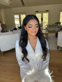 a woman with long black hair wearing a white shirt and feathers on her head standing in a living room