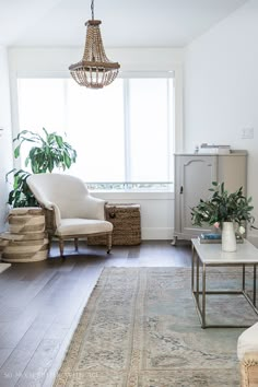 a living room filled with furniture and a chandelier hanging from the ceiling next to a window