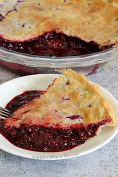 a piece of pie on a plate with a fork next to it and another pie in the background