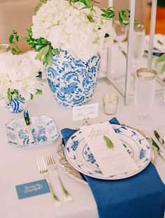 a blue and white table setting with flowers