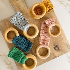 three knitted baby toys sitting on top of a wooden cutting board