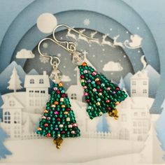 green christmas tree earrings with multicolored beads on silver earwires in front of a snow scene