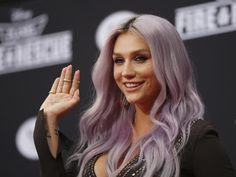 lady with long purple hair waves to the crowd while wearing an elaborate ring on her left hand